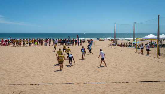 Lisbon. Portugal- 07.08.2023. People playing beach football with a large crowd of spectators at Carcavelos Beach.