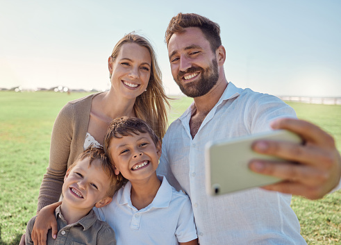 Nature, selfie and phone with happy family social media picture on a holiday together in outdoor green garden. Happy, smile and parents smile, photo and love bonding with children outside in a park