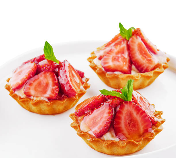 istock Tartlets with custard, strawberries and mint served on white plate 1545075550