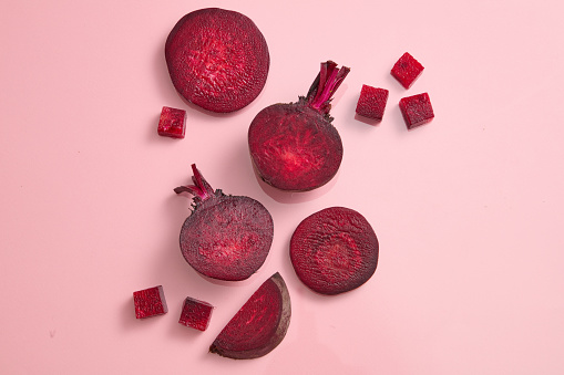 Beetroot cut in halves, slices and cubes are decorated against pink background. Beetroot (Beta vulgaris) can help people with heart failure and heart disease