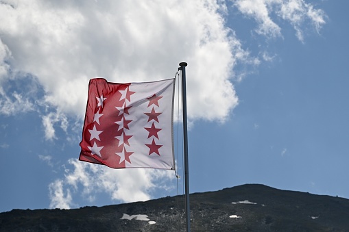 A closeup of Valais Canton flag on slope of a hill against the sky