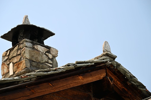 A low angle of a stone chimney against a blue sky