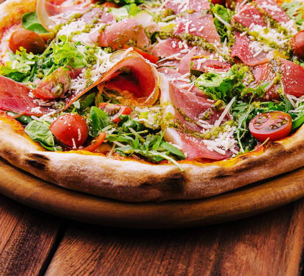 istock Pizza with prosciutto meat, cherry tomatoes, arugula and parmesan cheese 1545128399