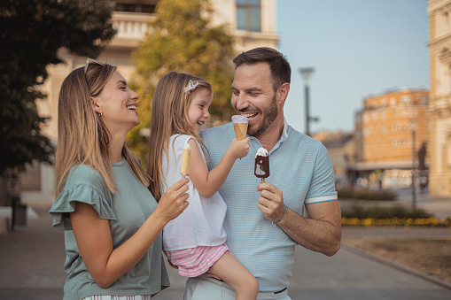 Authentic Happy Family Having Fun Together at Park With Little Girl Playing With Ice Cream - Lifestyle and Summer Concepts With Candid People