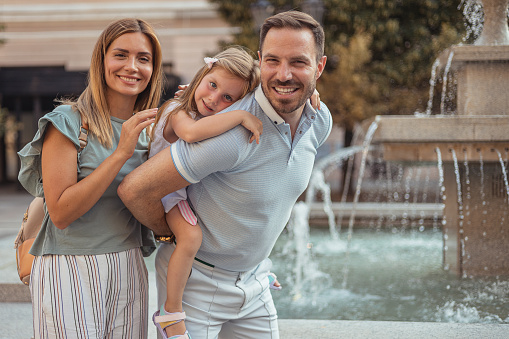 Happy Family With Man, Woman and Child Looking at Camera While Leaned on Each Other Outside. Family, Parenthood and People Concept