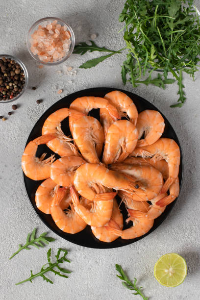 istock Boiled shrimps in a round plate and spices on light gray background, Top view 1545174575