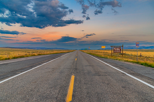 A sign welcoming drivers to the state of Colorado from Wyoming shot during a mid summer sunset.