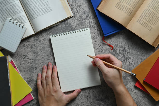 istock Overhead view of male hands writing in spiral notepad, diary planning goals or idea vision. 1545223105