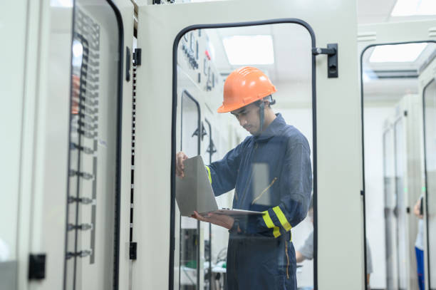 istock Asian electrical technician worker with personal safety equipment using laptop computer operating or check status from control panel switch board in control room of high voltage electric transformer station. Industrial business occupation worker concept. 1545224173