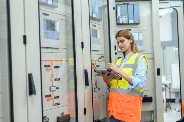 istock Caucasian electrical technician worker woman with personal safety equipment using digital tablet check list operating or check status from control panel switch board in control room of high voltage electric transformer station. 1545226265