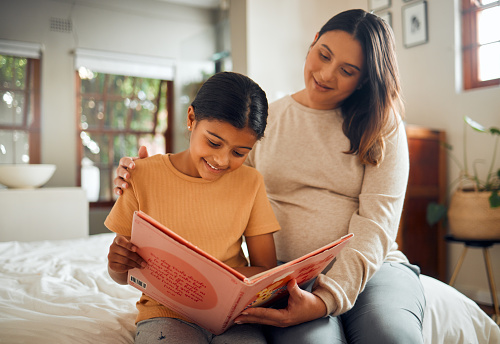 Pregnant mother reading to child for learning, language and home development help, support and bonding. Family, Indian people or mom and kid with storytelling book and creative education or teaching