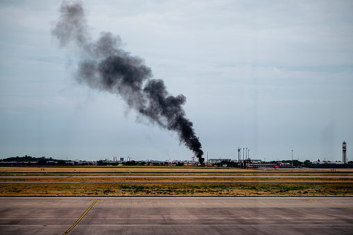 Dark smoke rising from the firefighter training site in Berlin. Seen from Berlin Brandenburg airport runway.