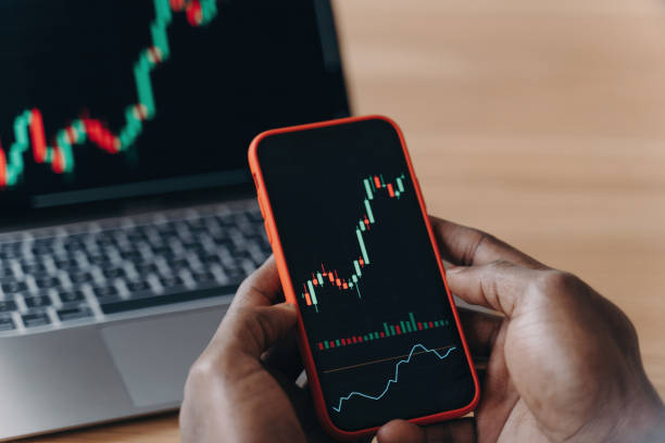 istock African hands holding smartphone and laptop, analyzing financial data graphs, trading stock market, investment purposes. 1545251218