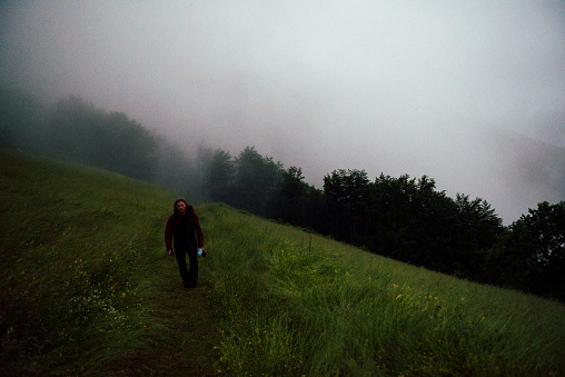 Man walking in rain through the fog in the foggy hilltops of Biogradska national park