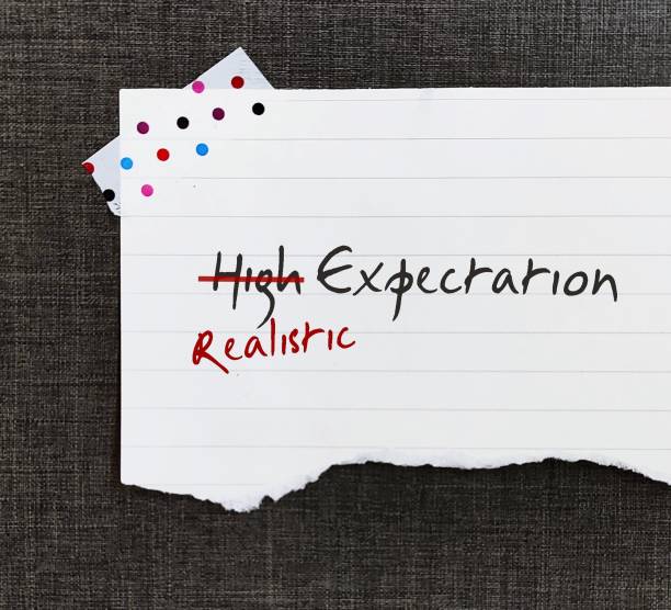 istock Stick note wallpaper with handwritten text HIGH EXPECTATION crossed HIGH off, replaced with REALISTIC, to be able to move forward in life with more acceptance when things turn out lower than expected 1545265019