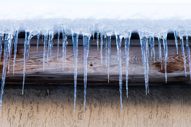 сосульки висят на крыше дома. таяние снега с крыши дома теплым зимним днем - melting ice icicle leaking стоковые фото и изображения