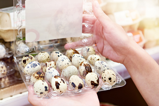 Hands woman with packages of quail eggs in store