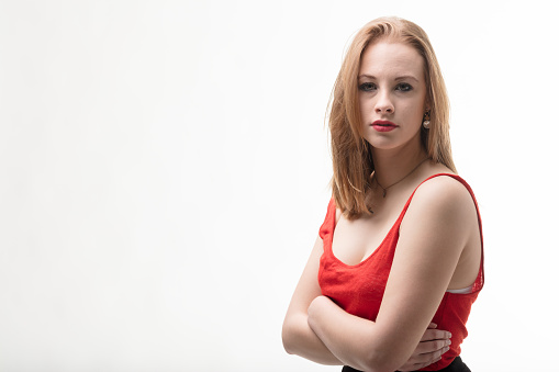 In a bright red tank top, a worried young woman self-hugs in consolation. She's cognizant of the women's only seemingly improved condition in the West. Ample copyspace