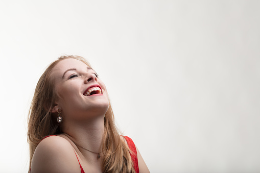 A young reddish-blonde woman dreams and wishes, her face turned upwards, expressing a wish or anticipating a surprise. Filled with joy and emotions, ample side copyspace