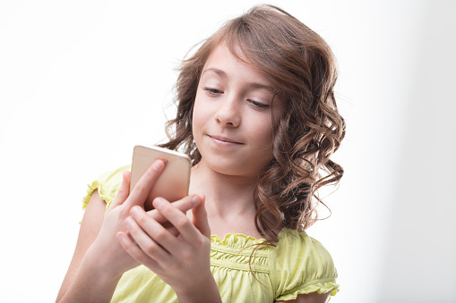 Competently using a smartphone, a curly-haired girl in green epitomizes the digital generation