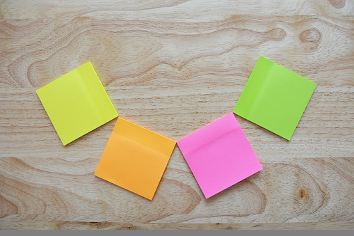 Blank colorful sticky notes on wooden surface.