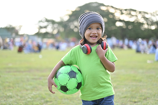 Asian toddler holding soccer ball in park