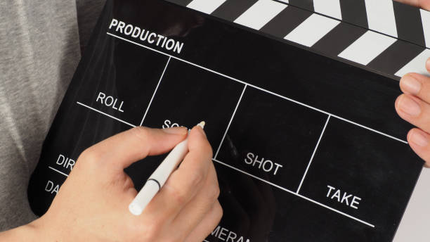istock The hand is holding a black clapper board and marker Pen on white background. 1545366288