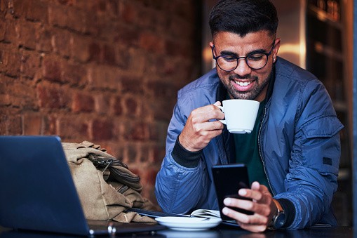 Black man, phone and coffee shop in the morning looking at a social media meme with happiness. Online communication, networking and cafe remote working of a freelance writer on mobile networking
