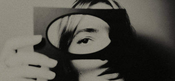 The portrait. Portrait of a beautiful woman. She partially covers her face with a passe-partout. The woman seems to be lost in thought or concentrating as she holds still for this portrait shot. Her facial expression is one of contemplation and perhaps introspection. Mystery. head shoot stock pictures, royalty-free photos & images