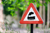 Railroad level crossing road sign without barrier or gate ahead, isolated beware of train roadside signage, grey pole post, large detailed horizontal closeup