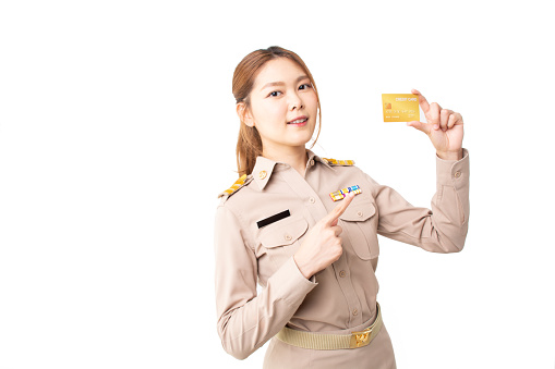 Female Thai government officer in khaki uniforms smiling and pointing on white background. Asian woman holding credit card for transaction money. Concept of advertising, payment purchase, financial.