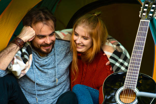 istock Laughing young couple sitting in camping tent hugging together 1545446311