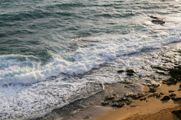 Beach with rocks and sea waves at sunset time