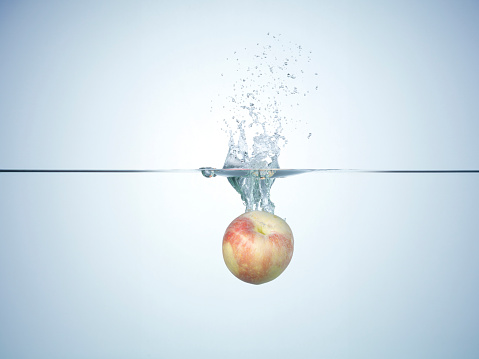 Fresh apple dropped in water. Apple splashing a lot of water droplets and bubbles you enter the water.