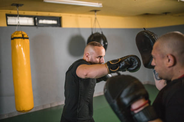 istock Man fighter sparring with his coach in a boxing gym 1545507905