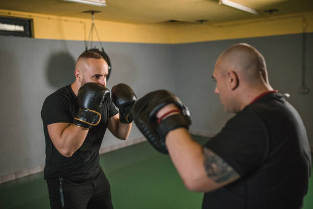 istock Strong boxer sparring with his coach in a boxing gym 1545526087