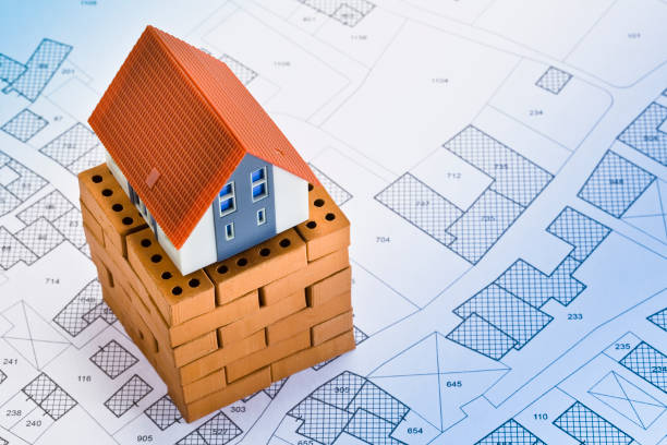 istock Cadastral map with buildings and home model with small terracotta bricks - house construction and building activity concept 1545596959