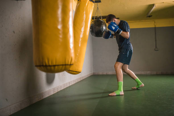 istock Confident man hits a punching bag in the gym 1545623181