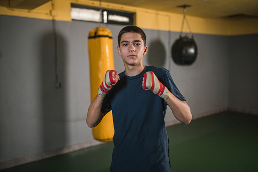 Portrait of a young generation Z boxer preparing for training in a boxing gym