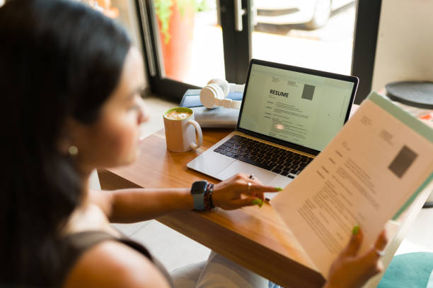 Rear view of a young woman working on her resume Young woman looking for a new job and sending her online CV resume using the internet zone of the coffee shop good cv stock pictures, royalty-free photos & images