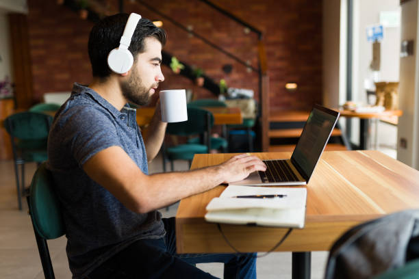 istock Freelancer man drinking coffee while working remotely in the coffee shop 1545692182