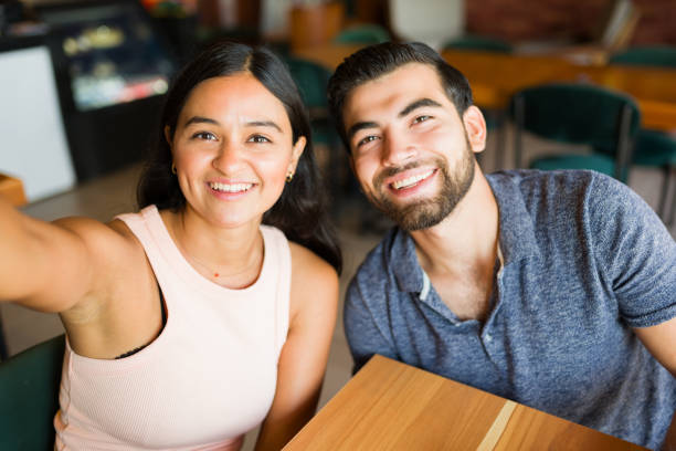 istock Hispanic couple taking a selfie during their coffee date 1545709560
