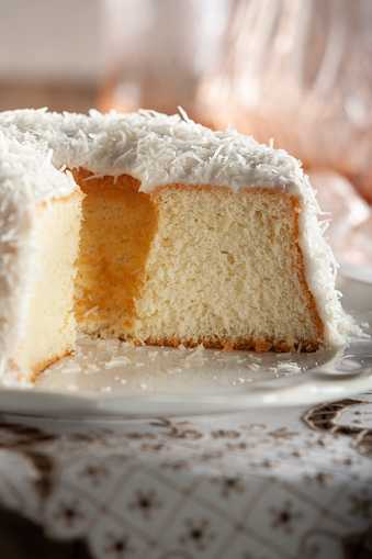 A sliced coconut cake on a plate over a table.