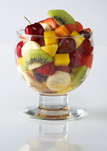 A bowl of fruit salad on a glass top.