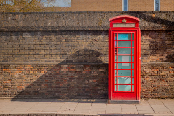 istock Red telephone booth over a brick wall in Cambridge. Old vintage 1545755183