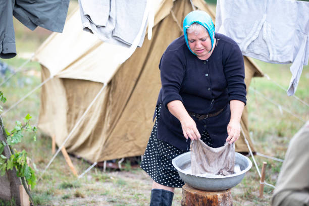 istock Refugee camp. Refugee woman doing laundry outdoors. 1545755363