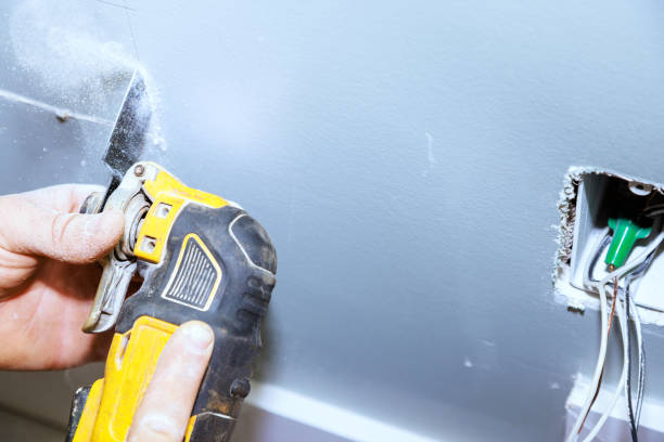 istock It is necessary to cut plasterboard with a multi-tool in order to lay a cable in wall using an electric cable hole 1545756981