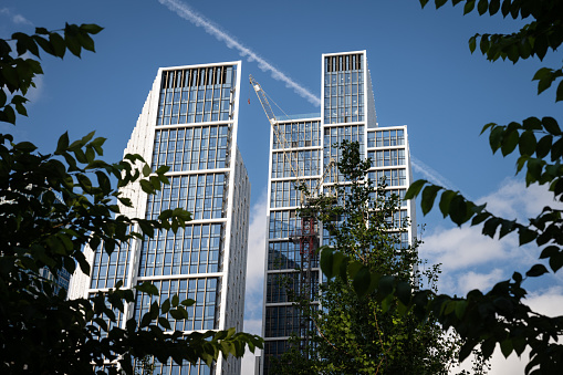 Nine Elms, London, UK: Tall buildings in Nine Elms, London: River Tower (Park Hyatt) (L) and City Tower (R) which comprise the One Nine Elms development with trees in foreground.