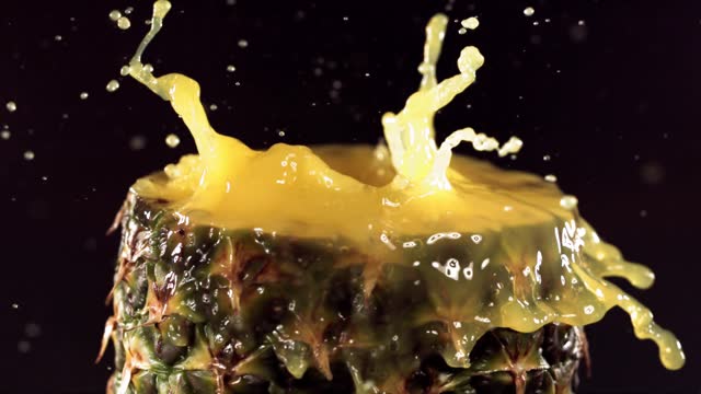 Pineapple pieces falling on the surface of half pineapple in slow motion.