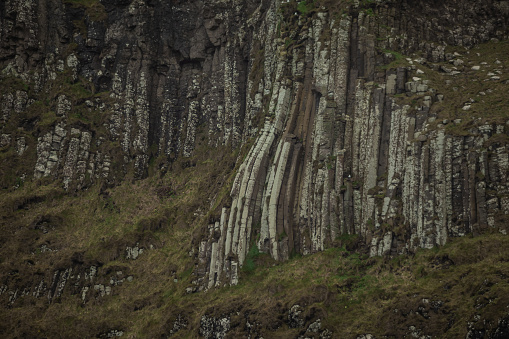 Detail of cliffs at Amphiteatre at Giants causeway in northern ireland, majestic basalt pillars at the beach on a cloudy day. Wide view of area..
